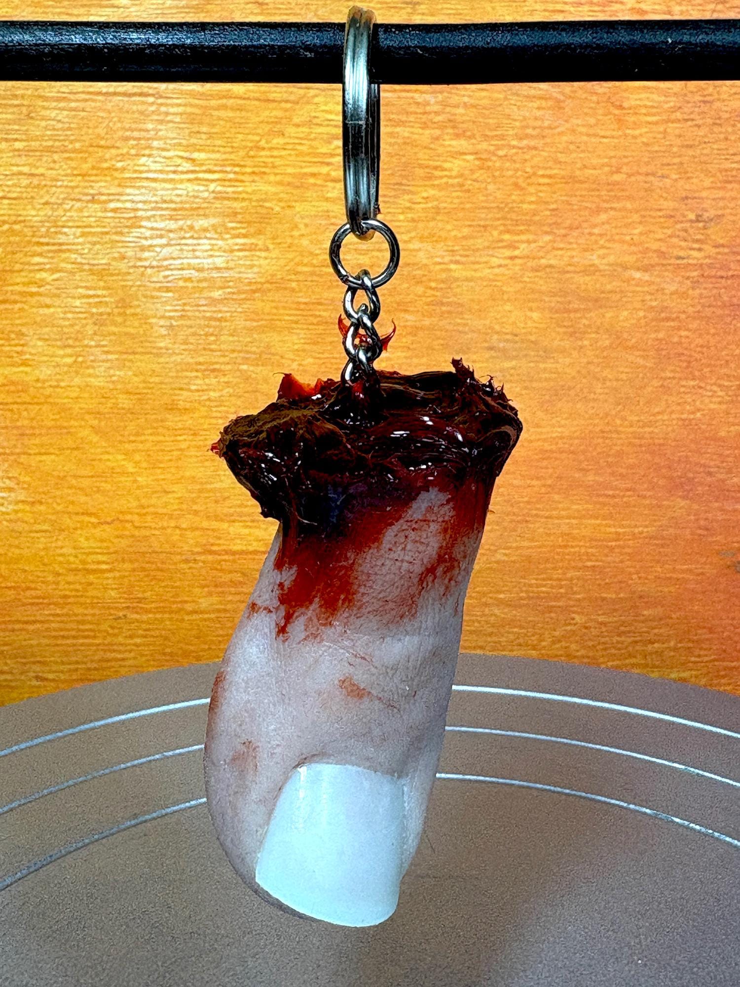 A novelty keychain shaped like a severed toe with a bloody wound.